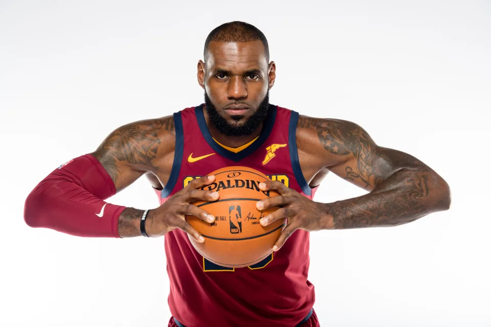 Basketballspieler LeBron James mit einem Ball in den Händen vor grauem Hintergrund