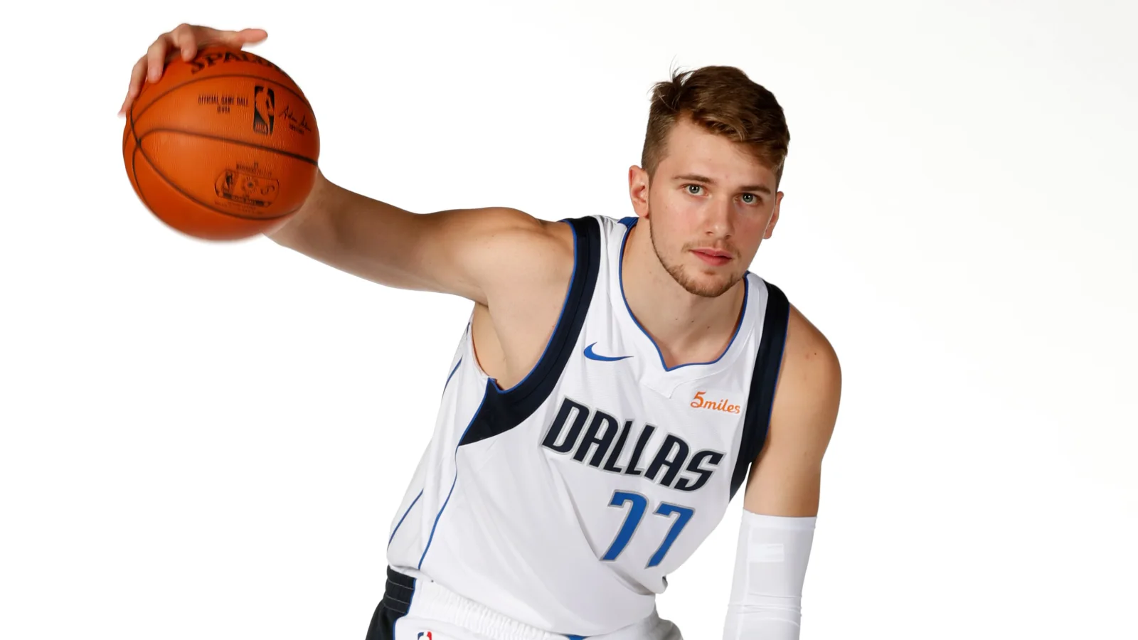 Slowenischer Basketballspieler Luka Dončić vor weißem Hintergrund mit einem Ball