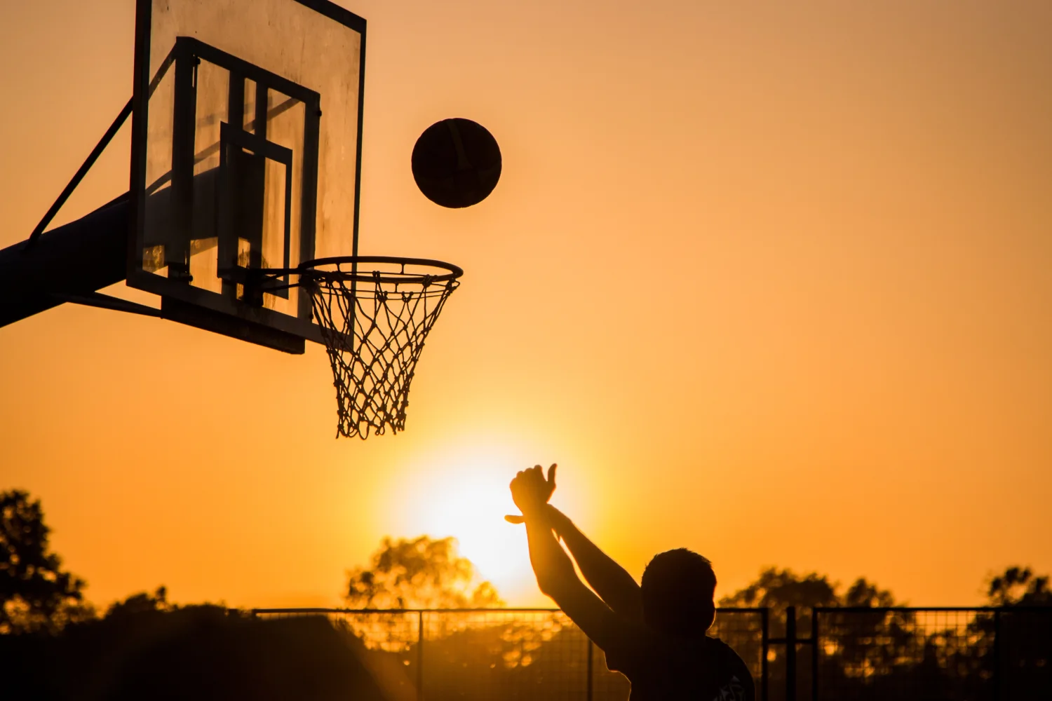 Wurf in Basketballkorb bei Sonnenuntergang