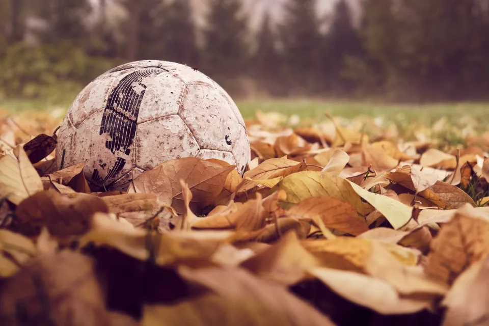 Alter Fußball in trockenem Laub