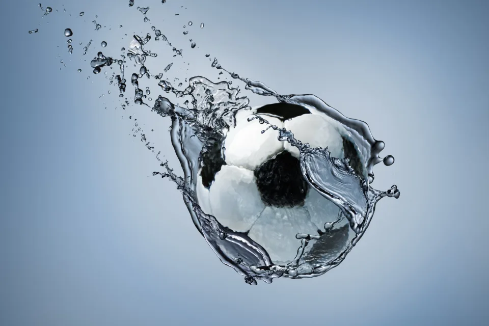 Fußball fliegt im Wasser vor grauem Hintergrund
