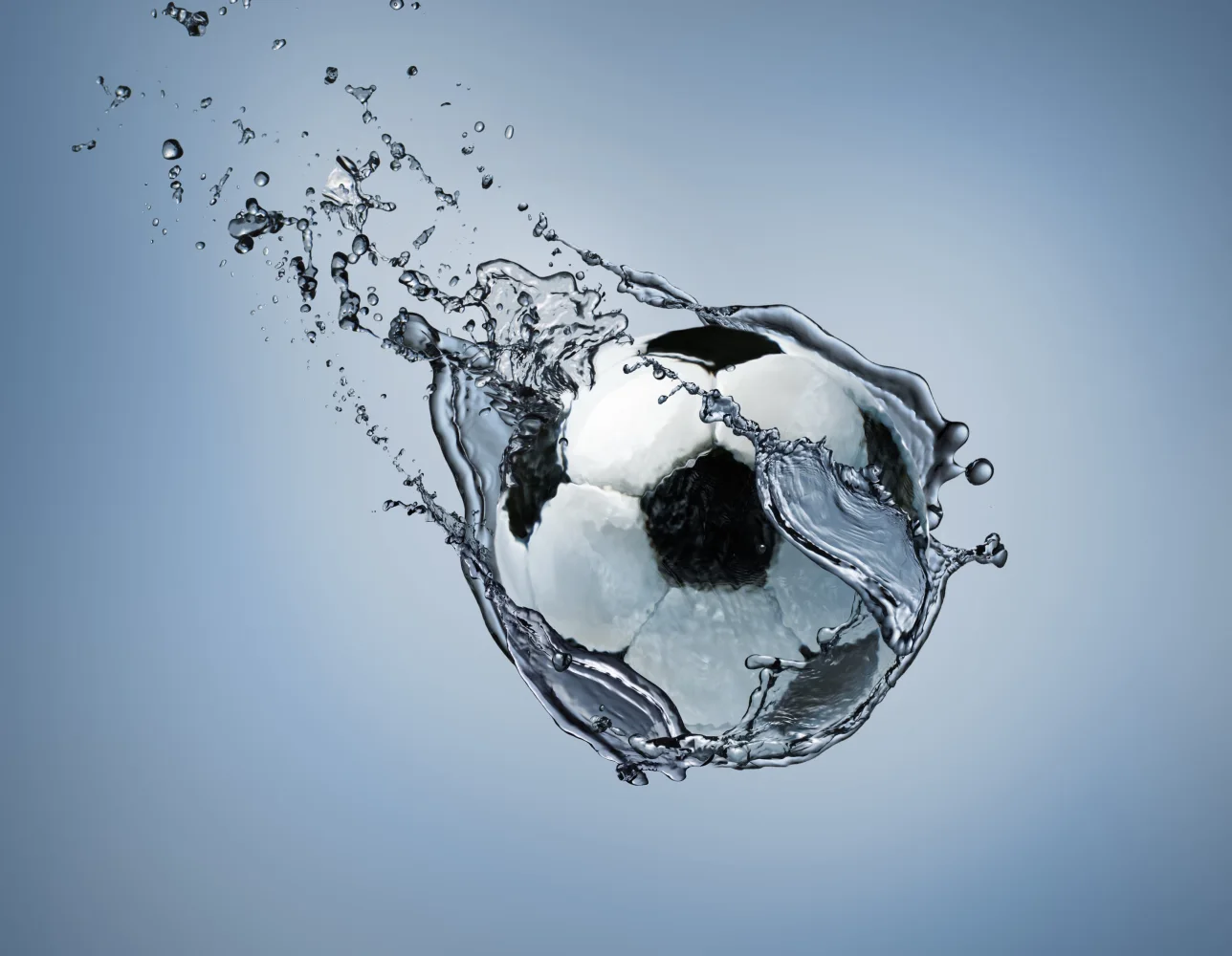 Fußball fliegt im Wasser vor grauem Hintergrund