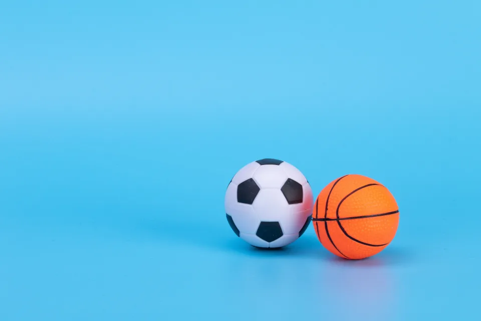 Fußball und Basketball vor hellblauem Hintergrund