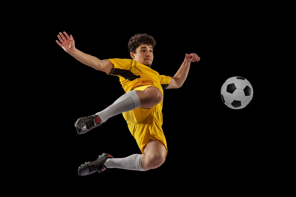 Mann Fußballspieler weicht ab Ball vor schwarzem Hintergrund