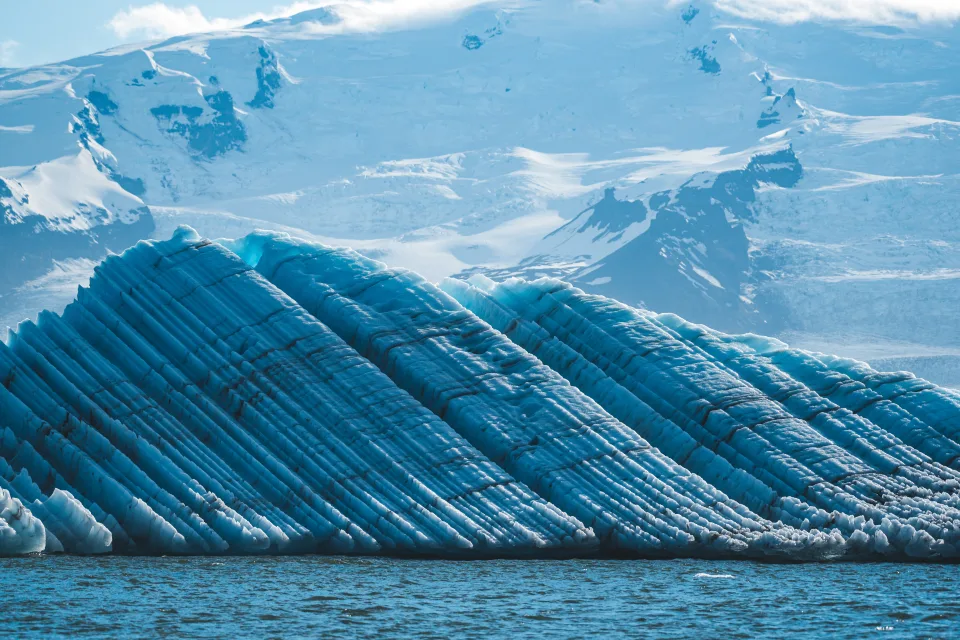 Großer hellblauer Gletscher und verschneite Berge Island