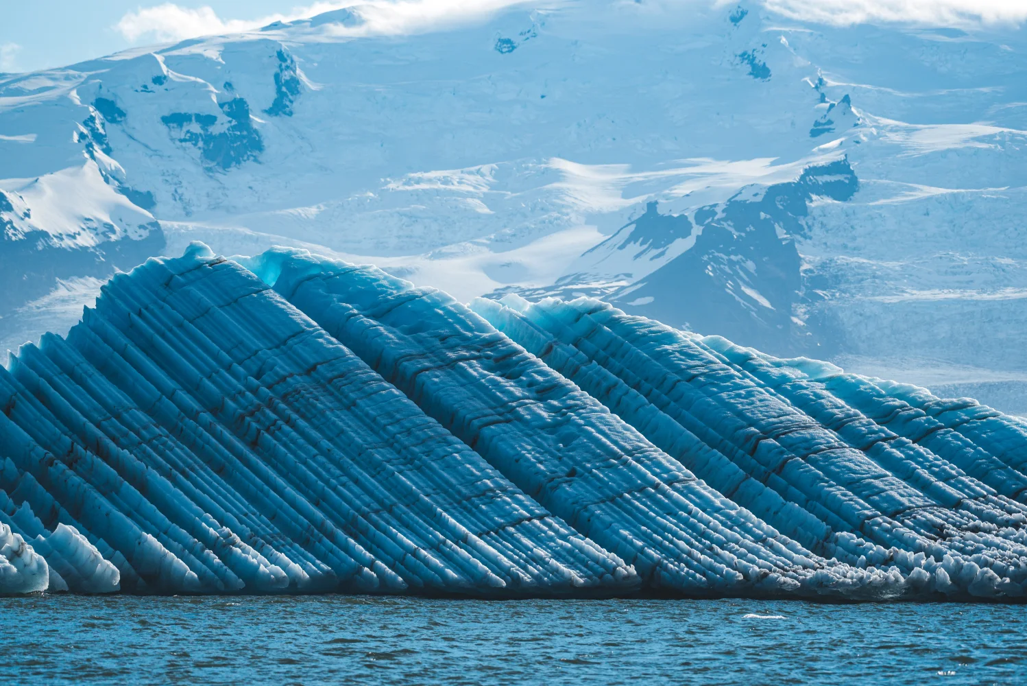 Großer hellblauer Gletscher und verschneite Berge Island