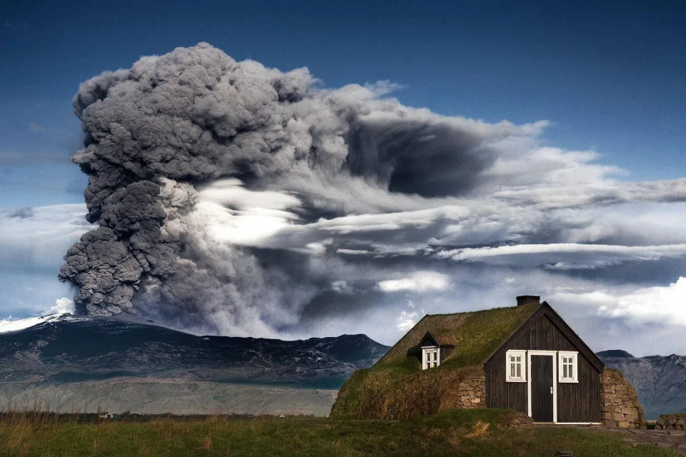 Haus in Island vor dem Hintergrund ausbrechenden Vulkan