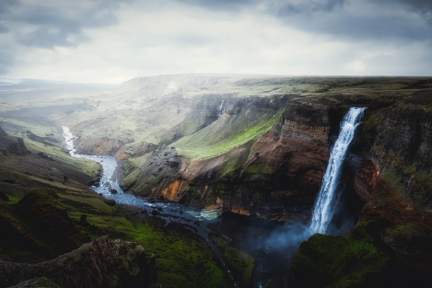 Wasserfall fließt mit Felsen in Canyon, Island