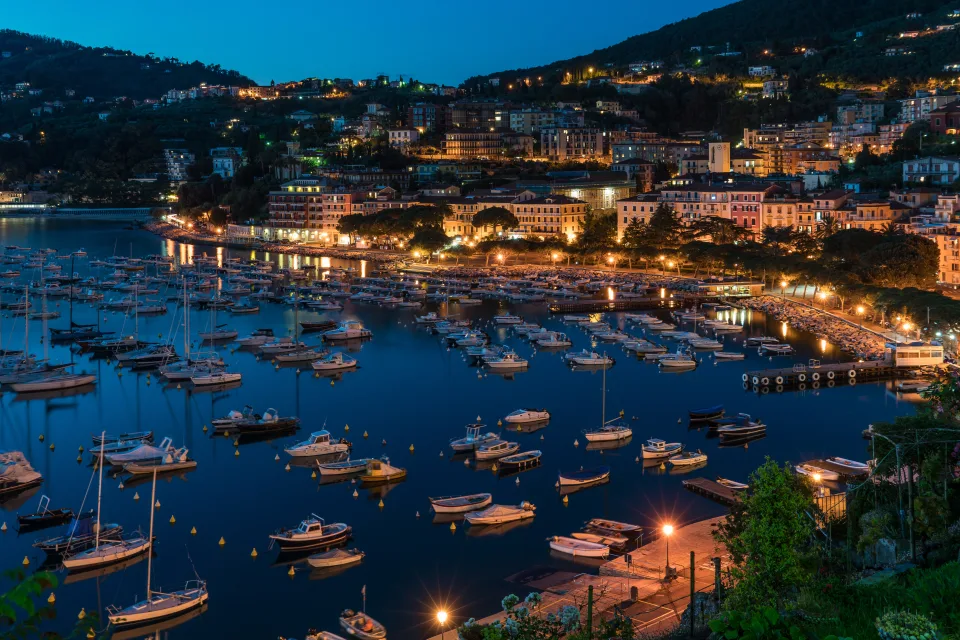 Panorama nächtlichen Stadt und Boote auf Bootssteg bei Küste, Ligurien. Italien