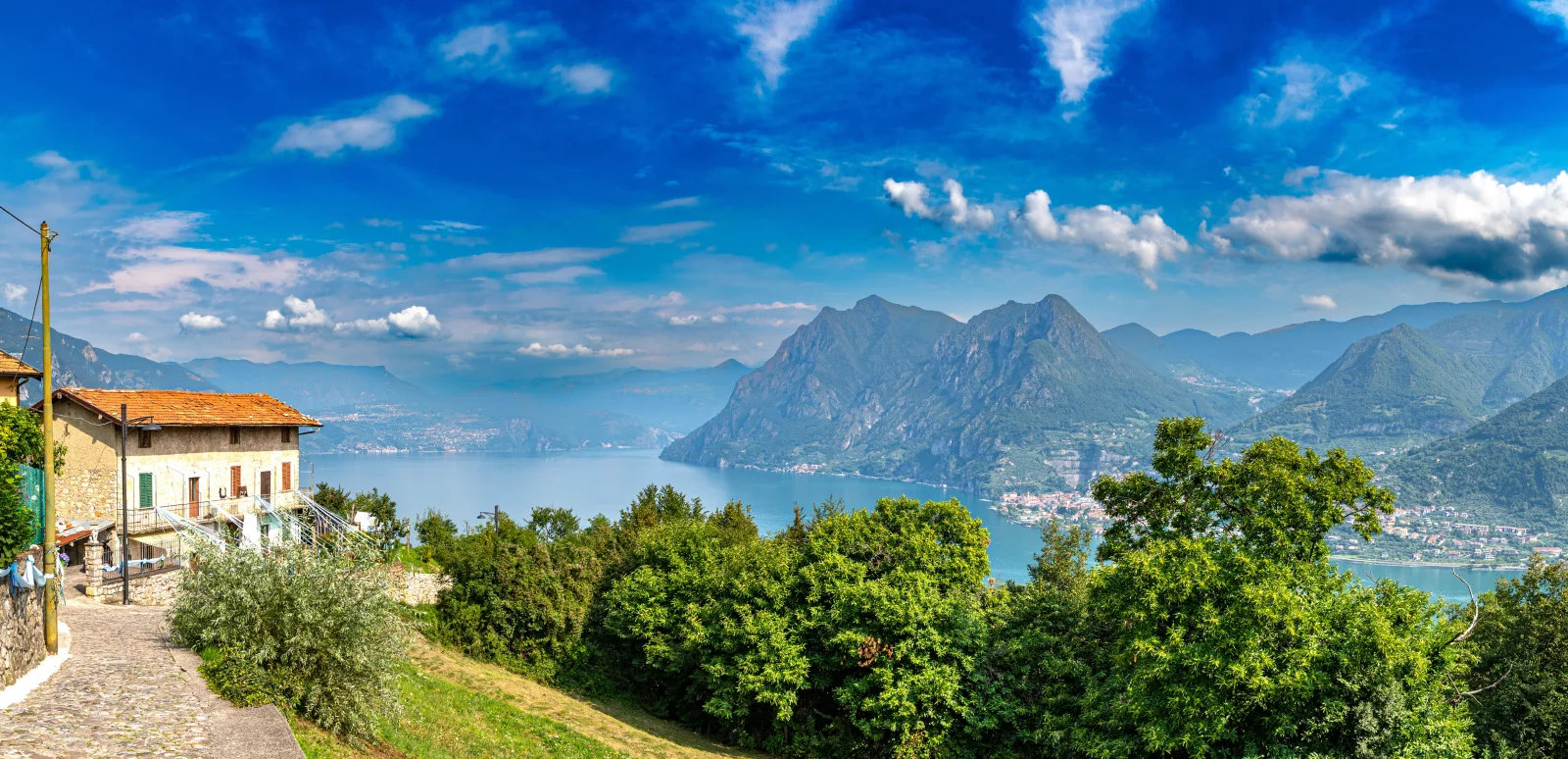 Schöner Blick auf See und Berge unter hellblauem Himmel, Italien
