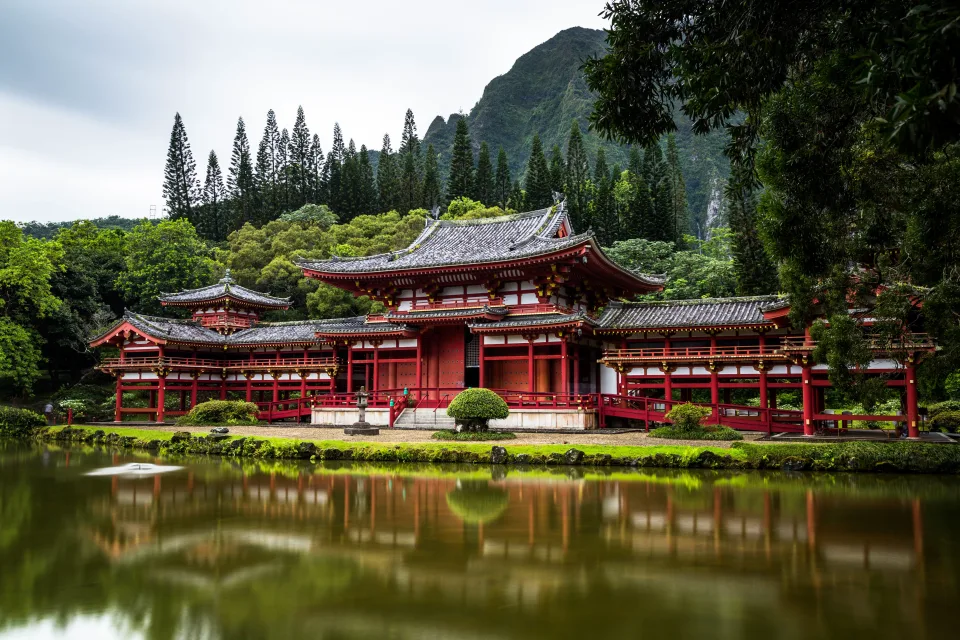 Rotes Gebäude Tempel am Wasser vor einer Bergkulisse, Japan
