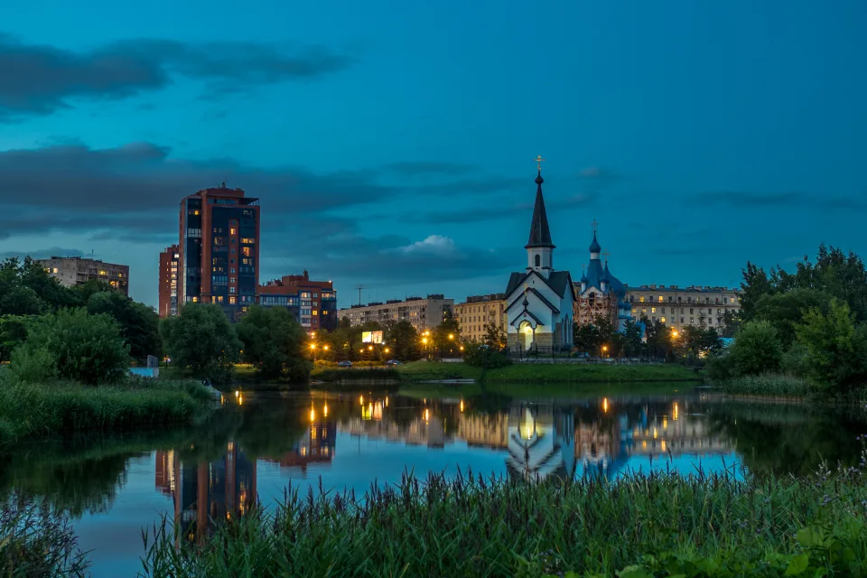 Abend Leuchten kleinen Kirche und Haus spiegeln sich im Wasser Teichs, Sankt Petersburg. Russland