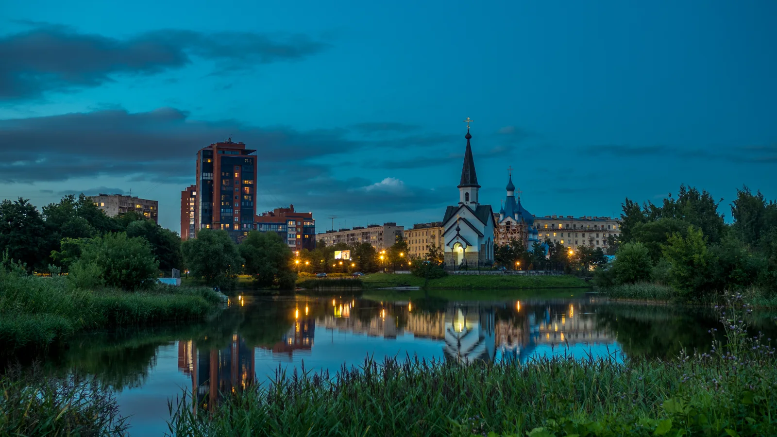 Abend Leuchten kleinen Kirche und Haus spiegeln sich im Wasser Teichs, Sankt Petersburg. Russland