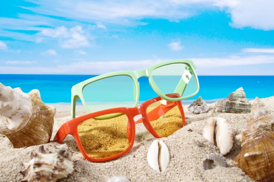 Brille im Sand mit Muscheln am Meer im Sommer