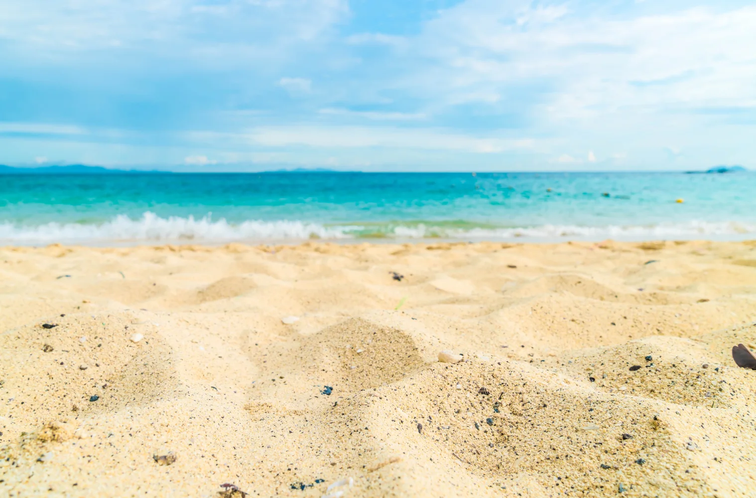 Heißer gelber Sand am Strand bei Ozean im Sommer
