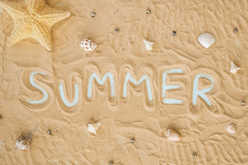 Schriftzug summer auf gelbem Sand mit Muscheln und Meeres Stern