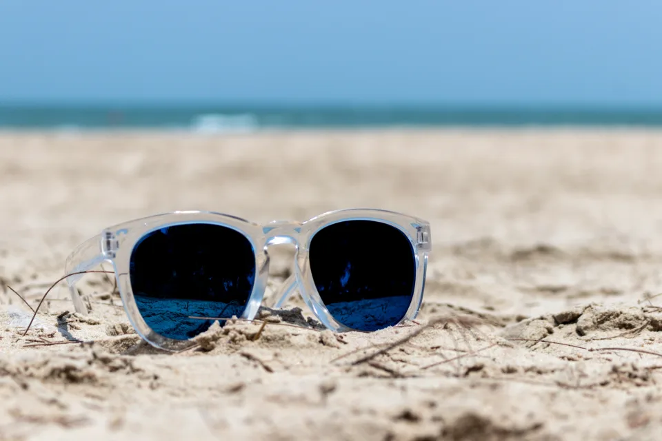 Sonnige Brille liegen im Sand am Strand im Sommer