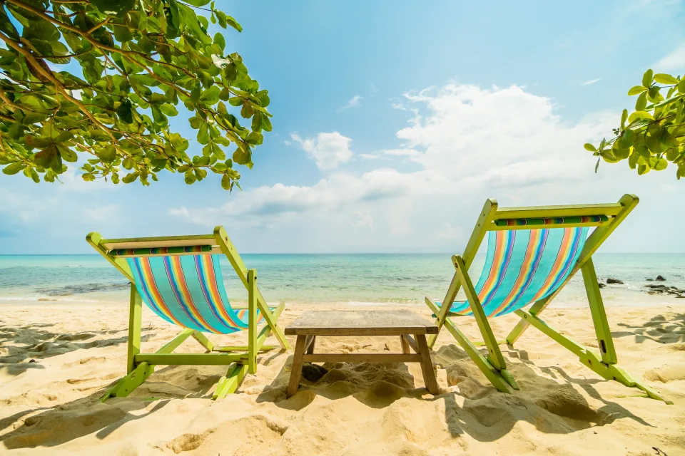 Zwei Liegestuhls am Strand unter hellblauem Himmel im Sommer