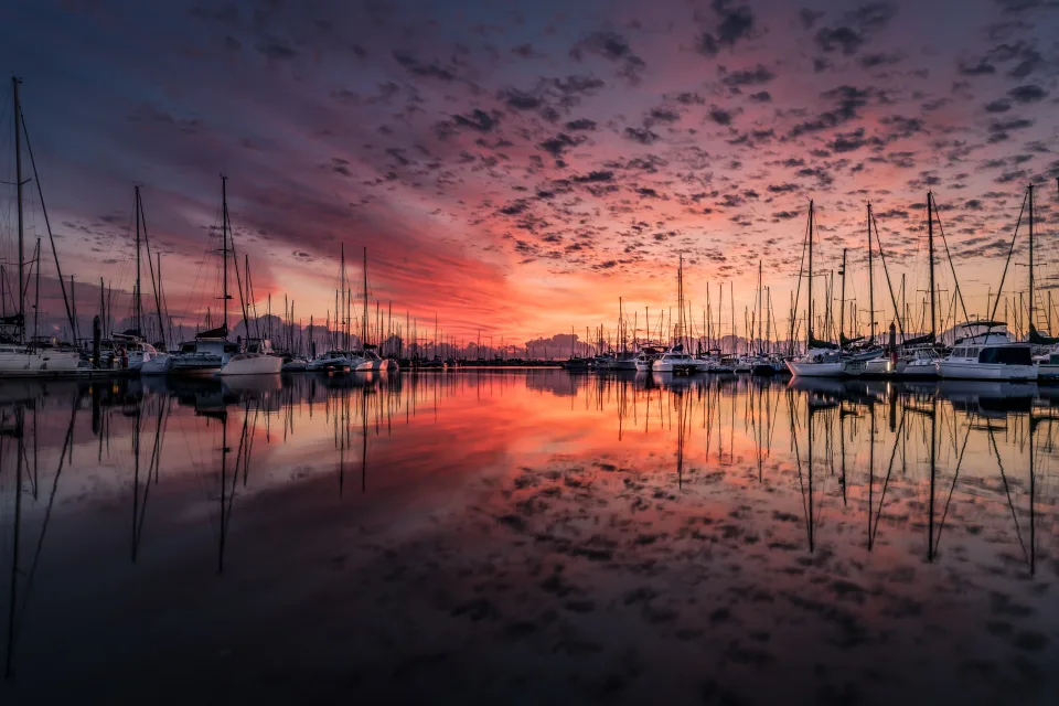 Boote bei Bootssteg im Wasser bei Sonnenuntergang