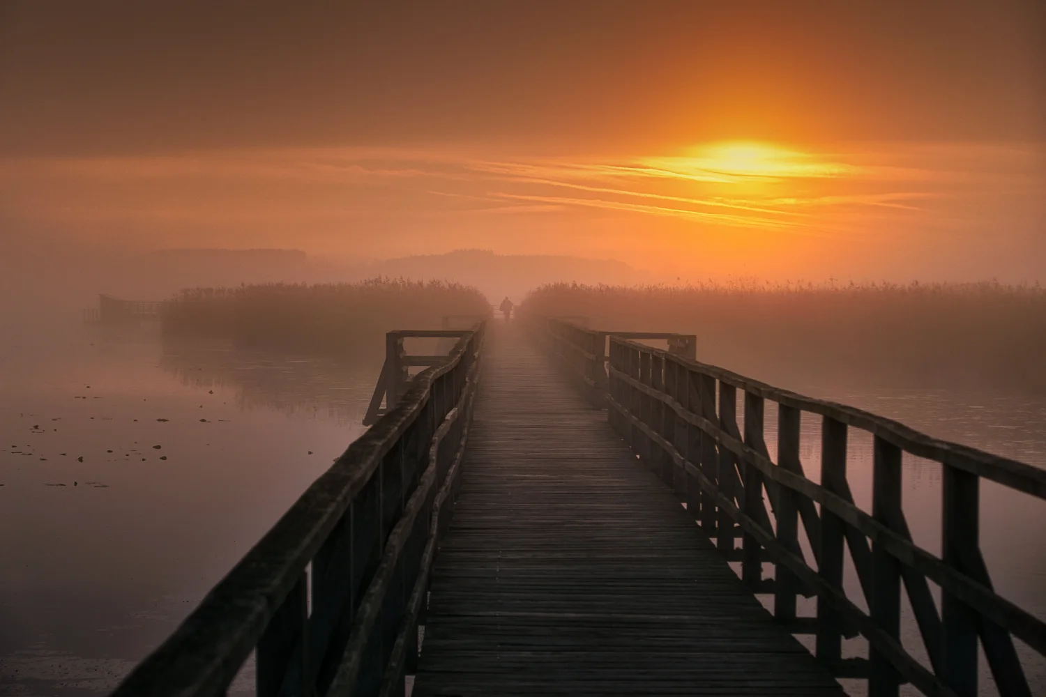 Hölzerner Brücke über Fluss bei Sonnenuntergang