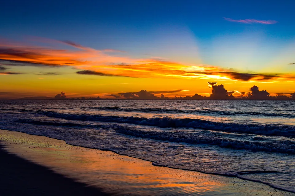 Leuchtende Strahlen Sonne bei Sonnenuntergang über dem Meer
