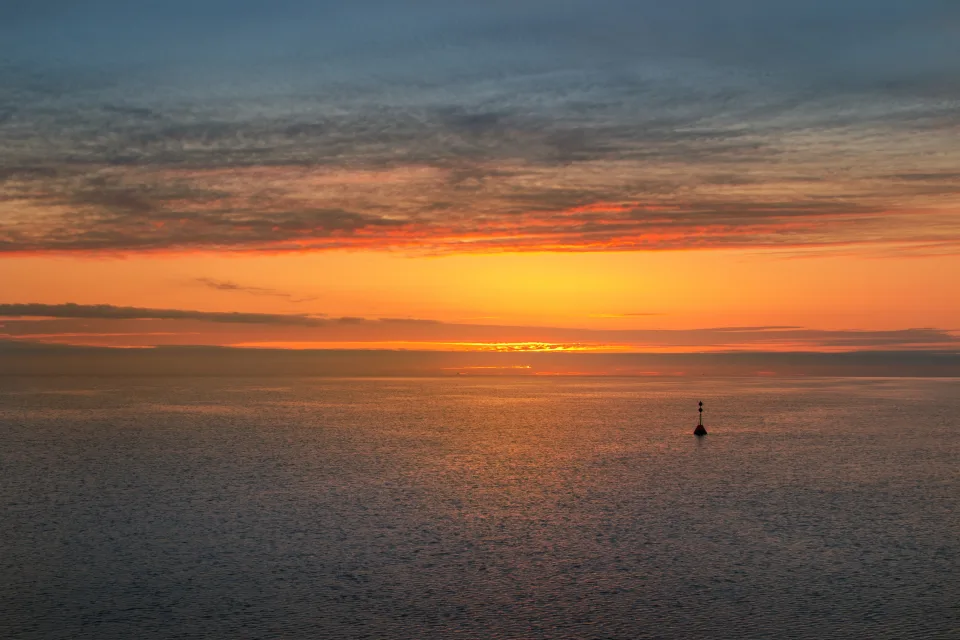 Leuchtender orangefarbener Sonnenuntergang auf Meeres Horizont