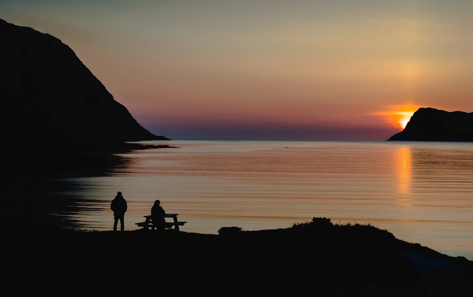Sonne verschwindet hinter Berg in Bucht