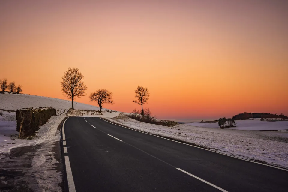 Straße vor dem Hintergrund roten Sonnenuntergang im Winter