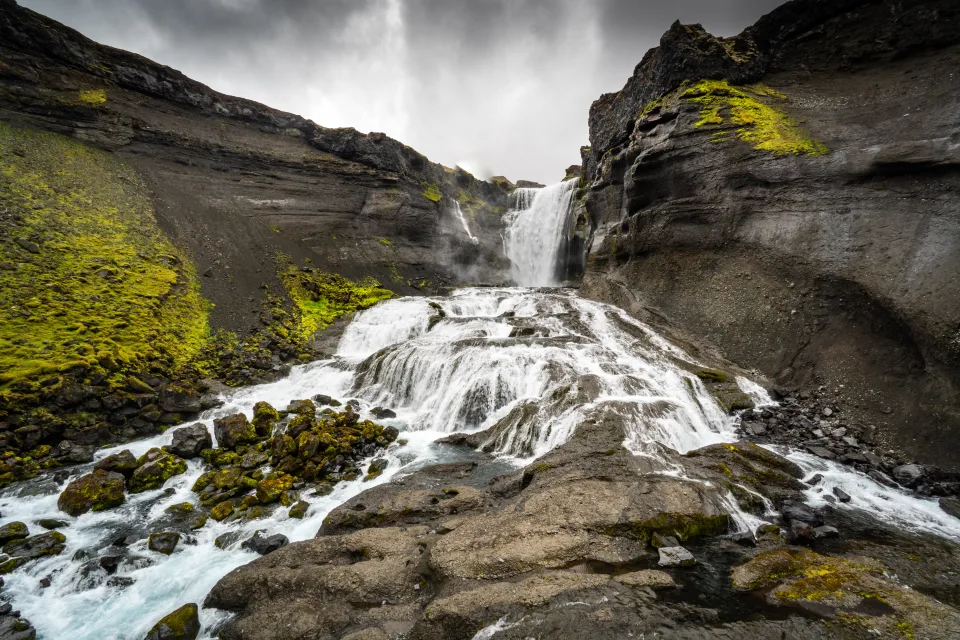 Schneller Berg Wasserfall unter grauem Himmel