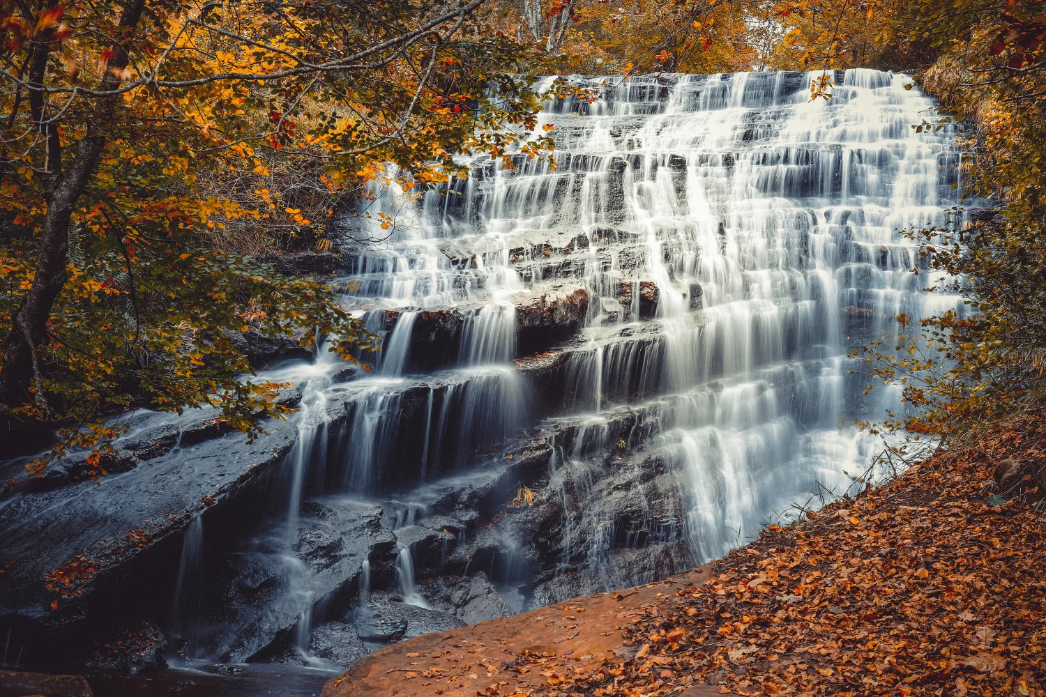 Schnelles Wasser Wasserfall fließt entlang Felsen im Herbst