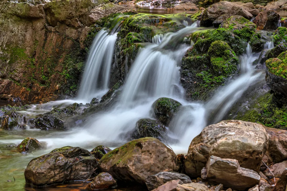 Schnelles Wasser Wasserfall fließt über Felsen im Herbstwald