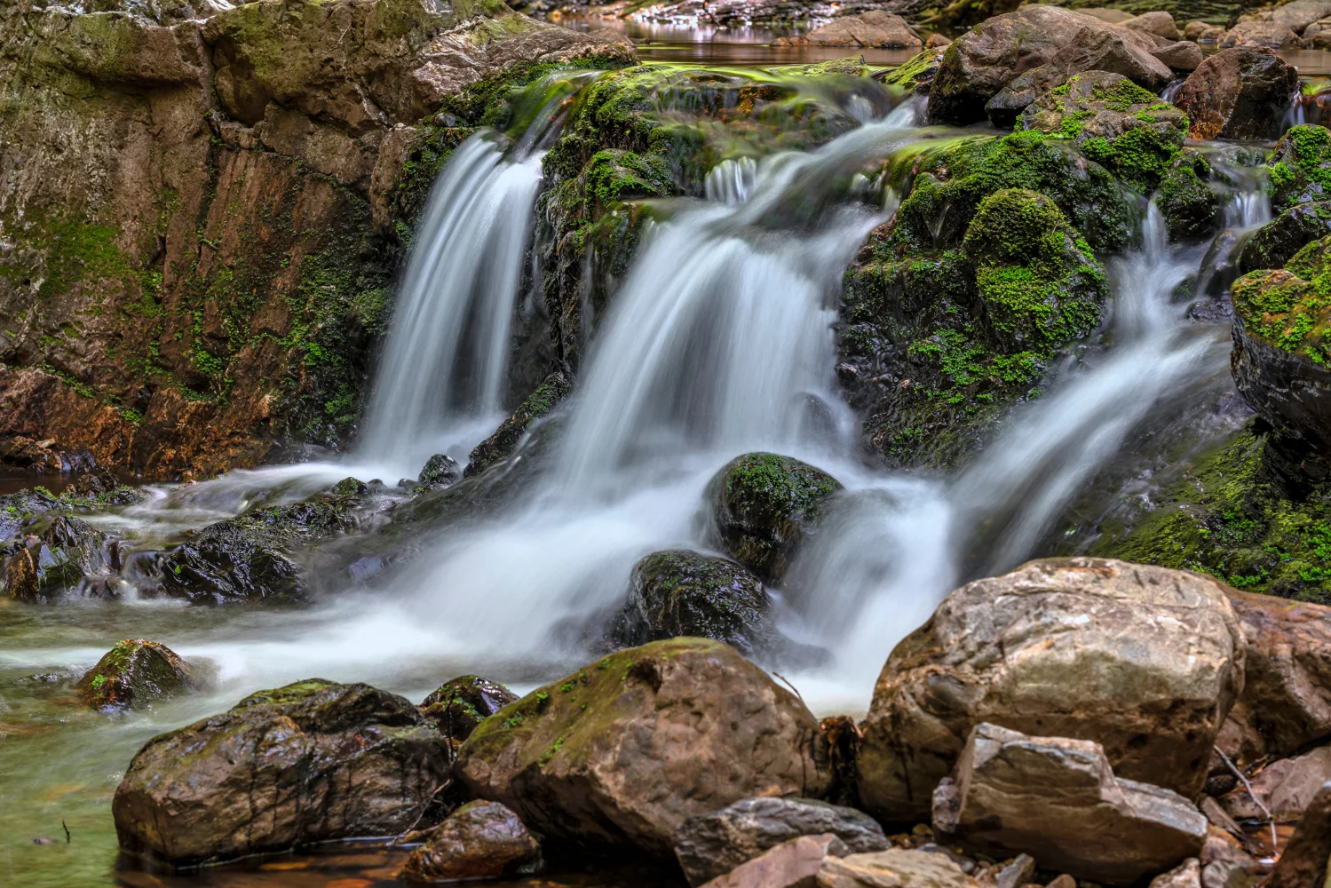 Schnelles Wasser Wasserfall fließt über Felsen im Herbstwald
