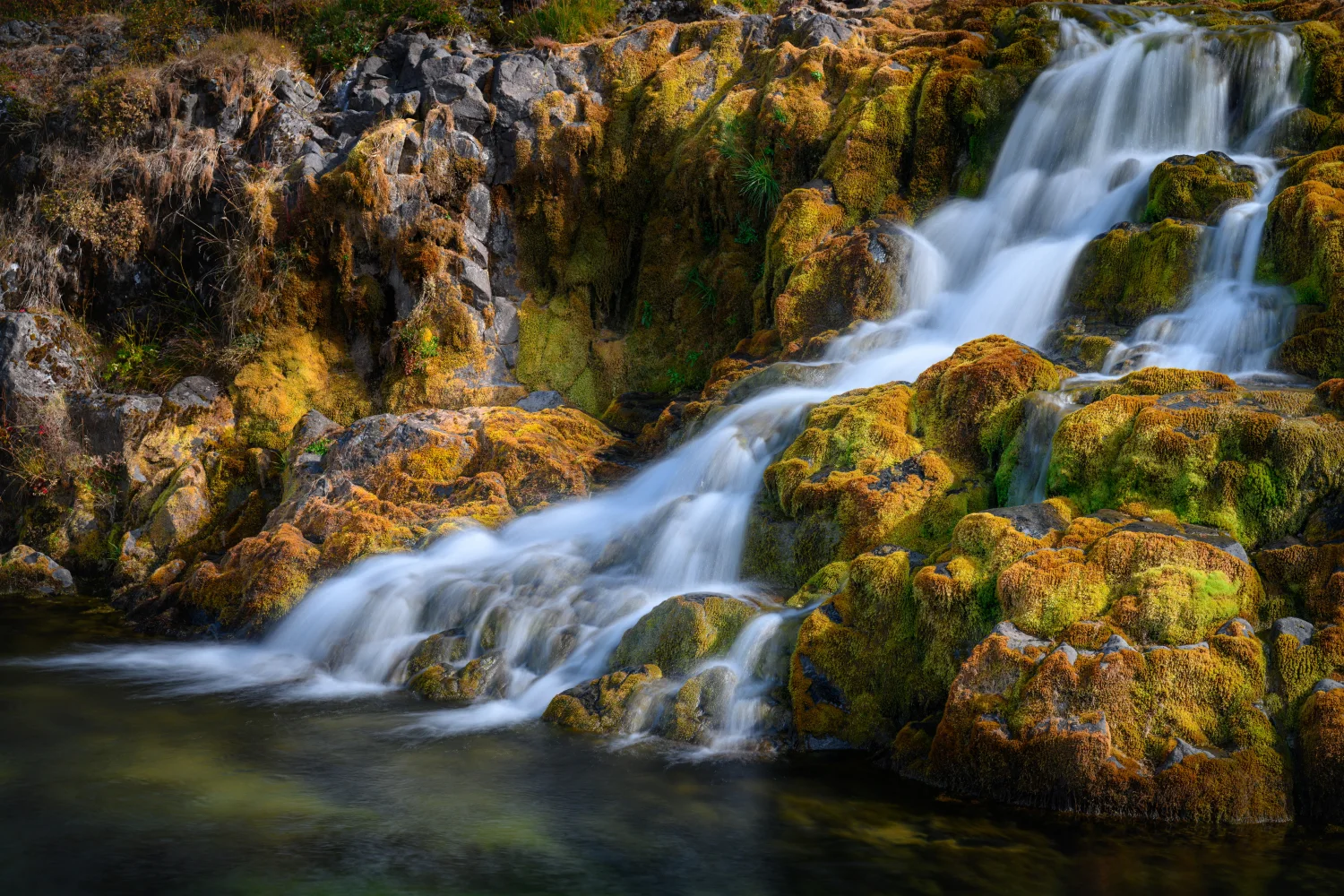 Schnelles Wasser Wasserfall fließt über moosbewachsene Steine, Island