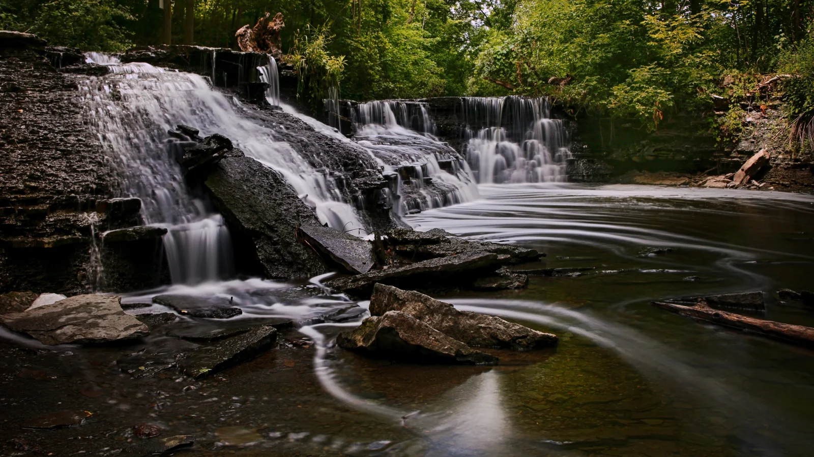 Schnelles Wasser fließt über Felsen Wasserfall im Park