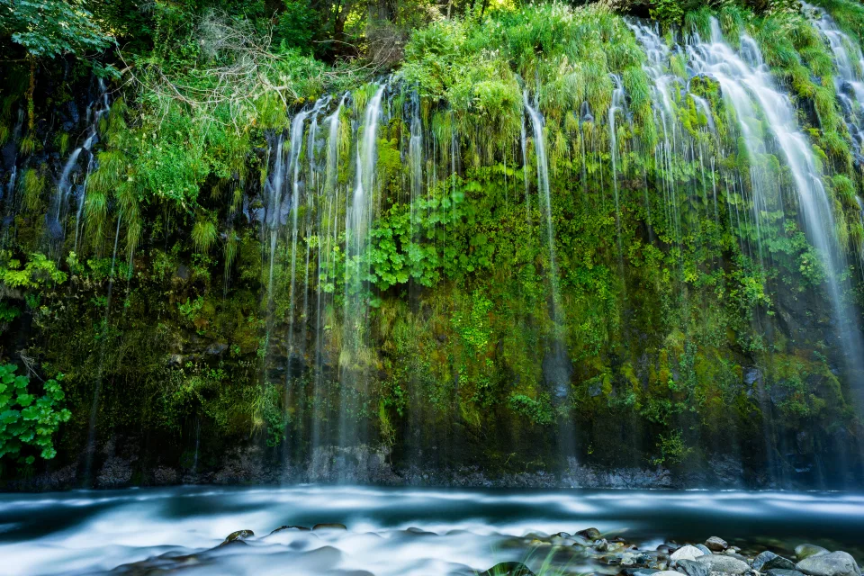 Schöner Wasserfall fließt entlang bedecktem Grün Klippen