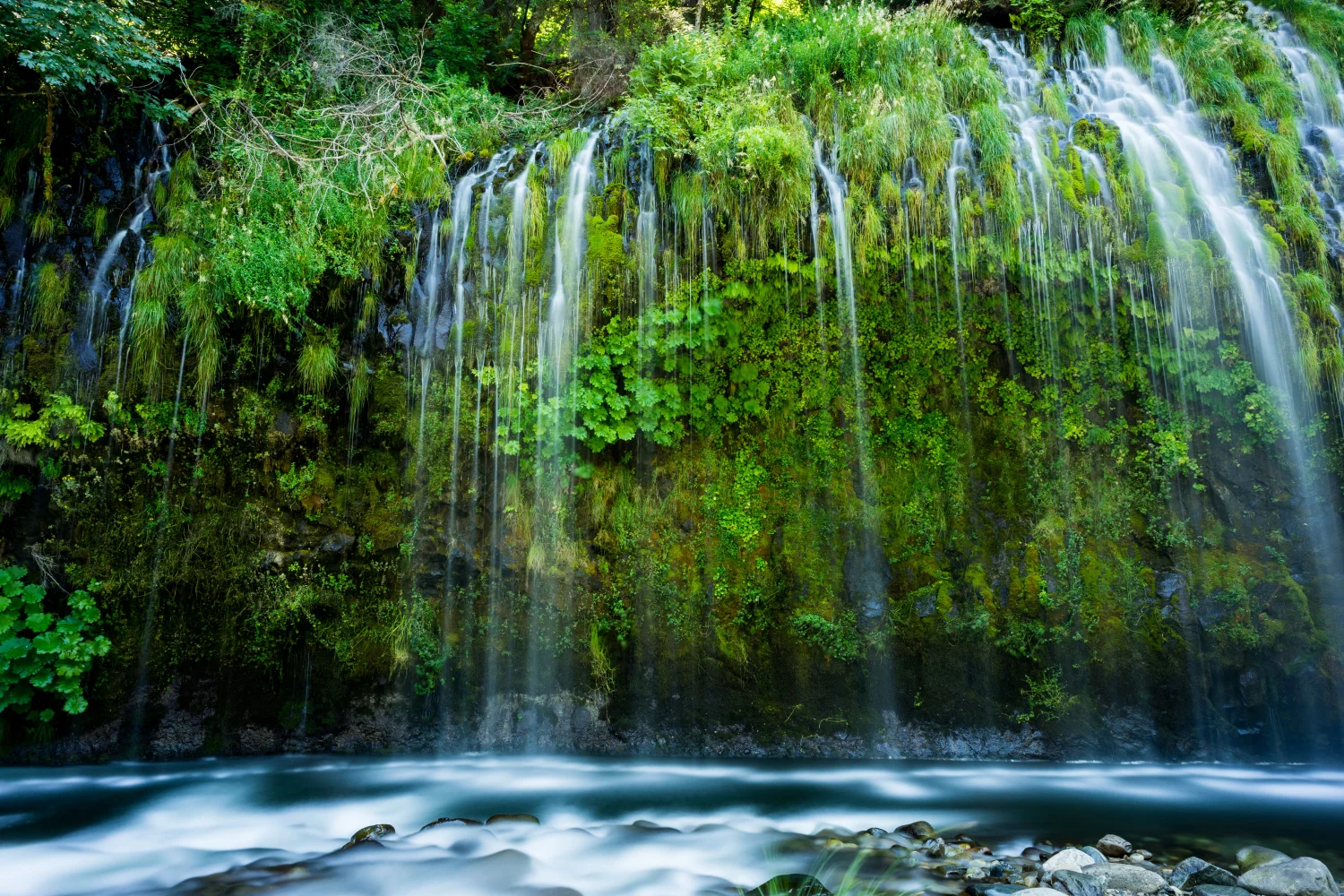 Schöner Wasserfall fließt entlang bedecktem Grün Klippen