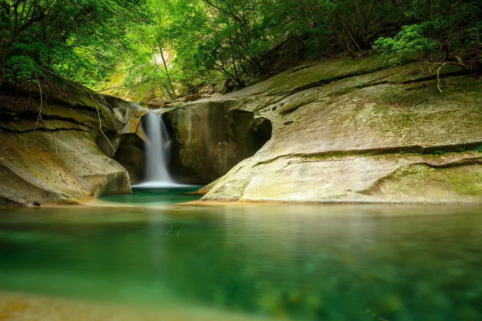 Wasserfall fließt entlang Felsen in See im Wald