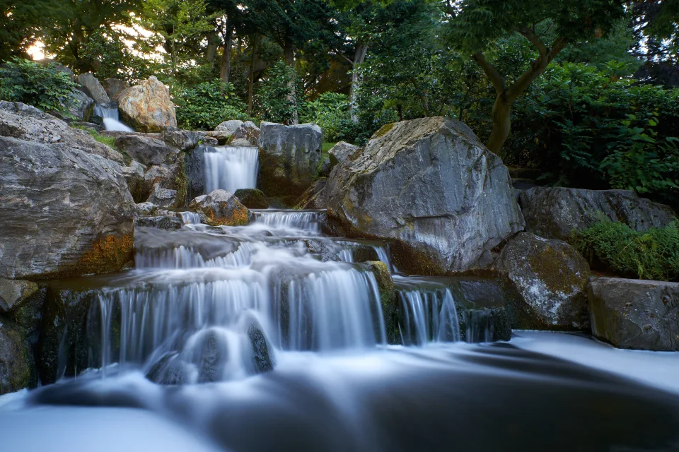 Wasserfall fließt entlang großem kaltem Felsen im Wald