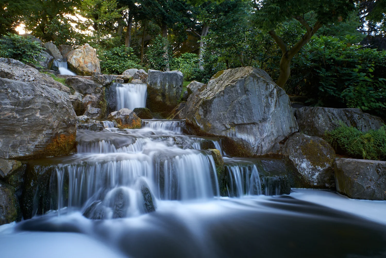 Wasserfall fließt entlang großem kaltem Felsen im Wald