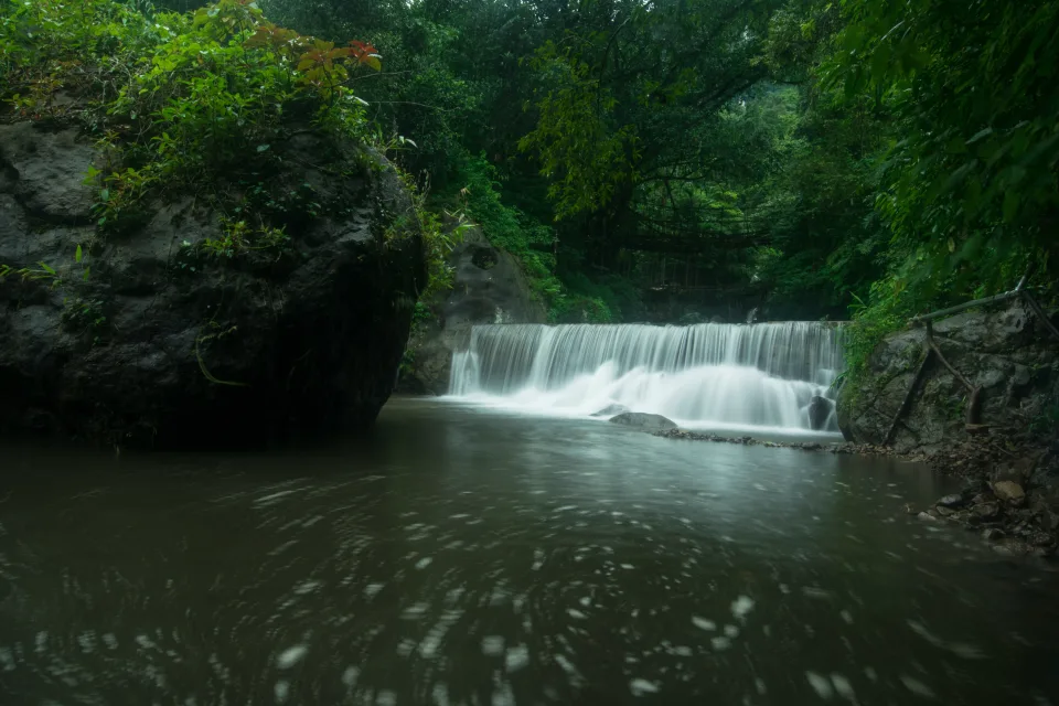 Wasserfall fließt im Fluss mit großen Felsen im Wald