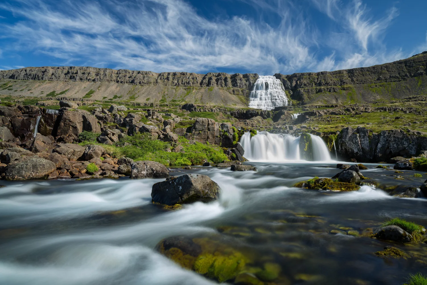 Wasserfall fließt mit Berg vor dem Hintergrund schönen hellblauen Himmel Island