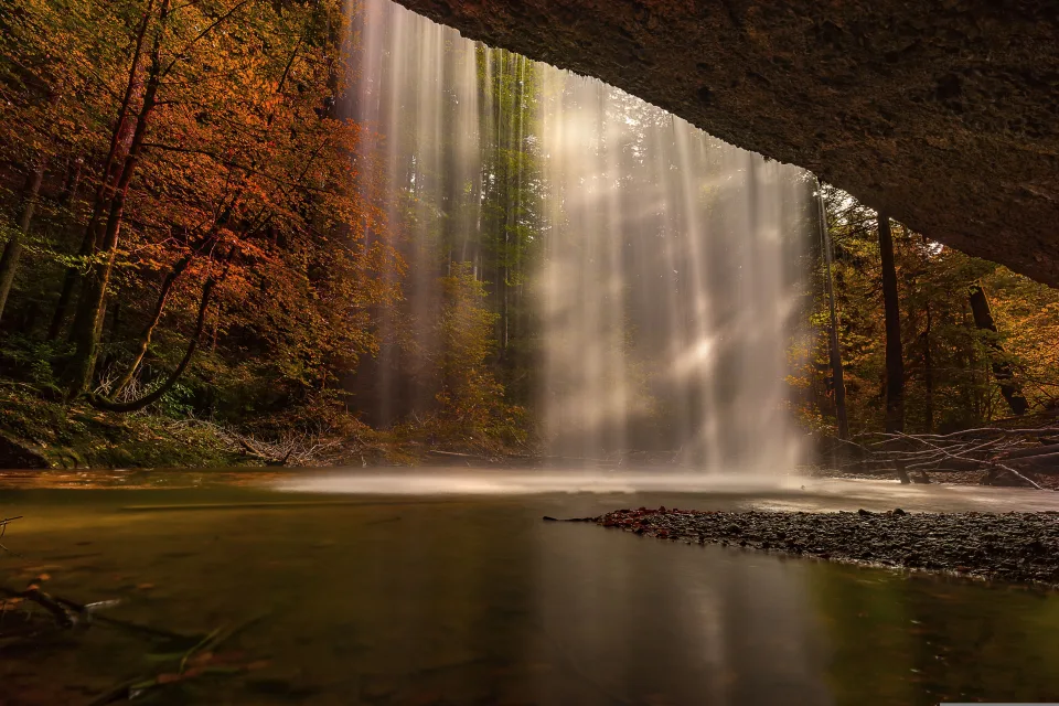 Wasserfall fließt mit Felsen im Herbstwald