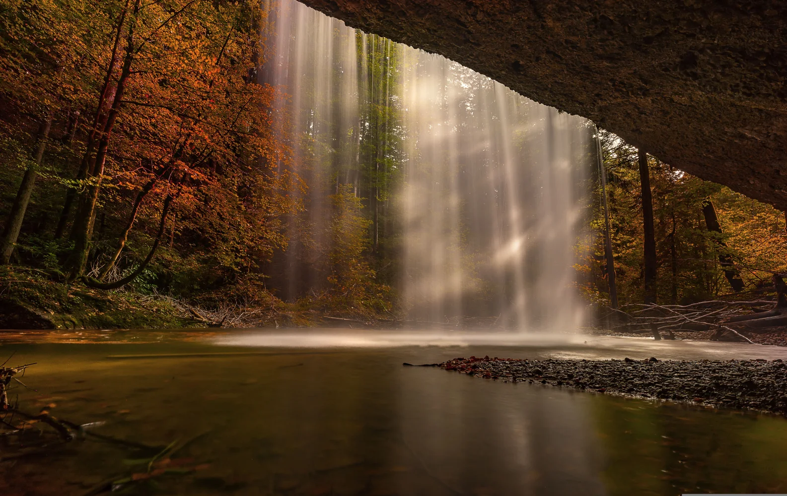 Wasserfall fließt mit Felsen im Herbstwald