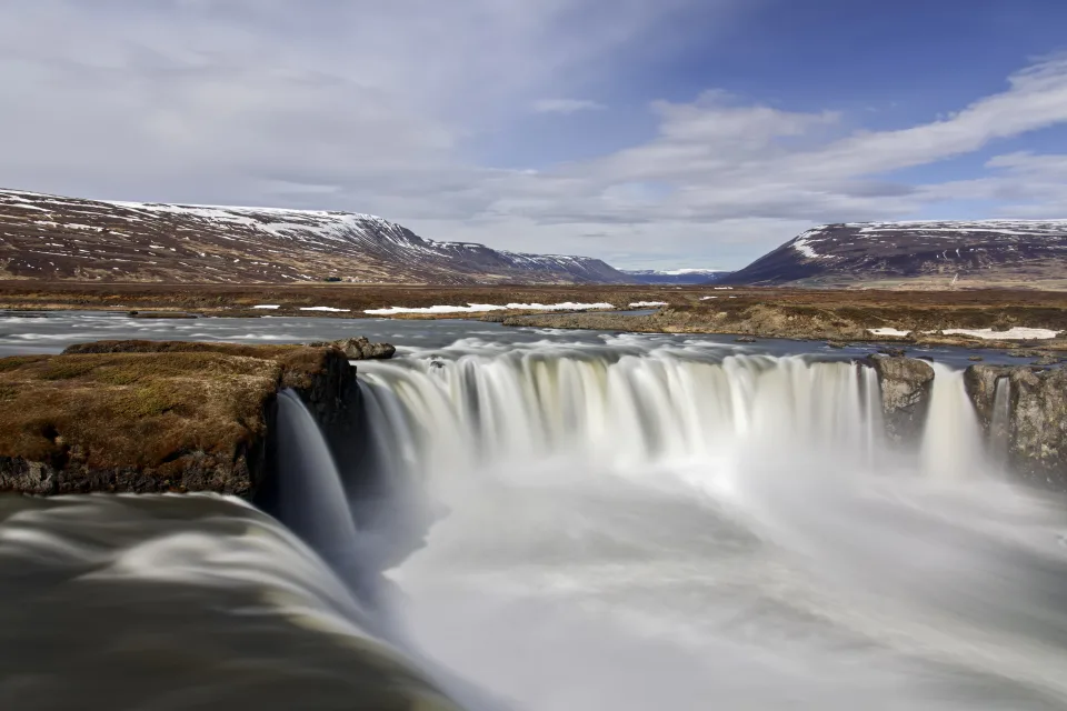 Wasserfall fließt vor einer Bergkulisse