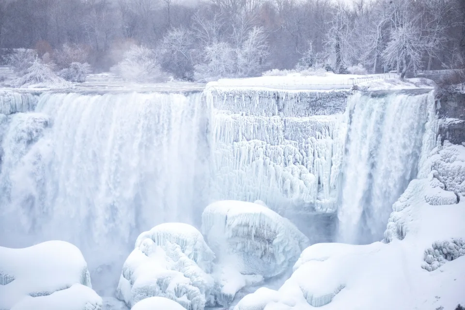 Zugefrorener Wasserfall fließt über Steine im Winter