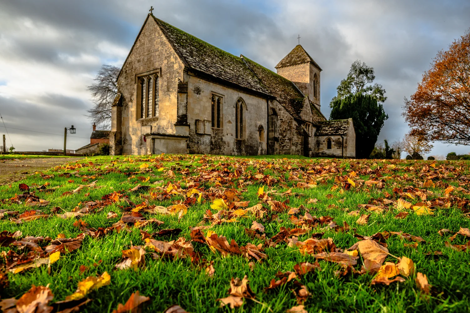 Gefallene Blätter auf grünem Gras bei alten Kirche im Herbst