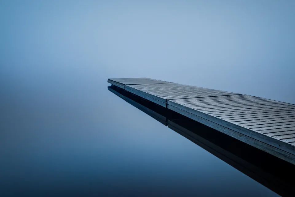 Hölzerner Brücke am See im Nebel