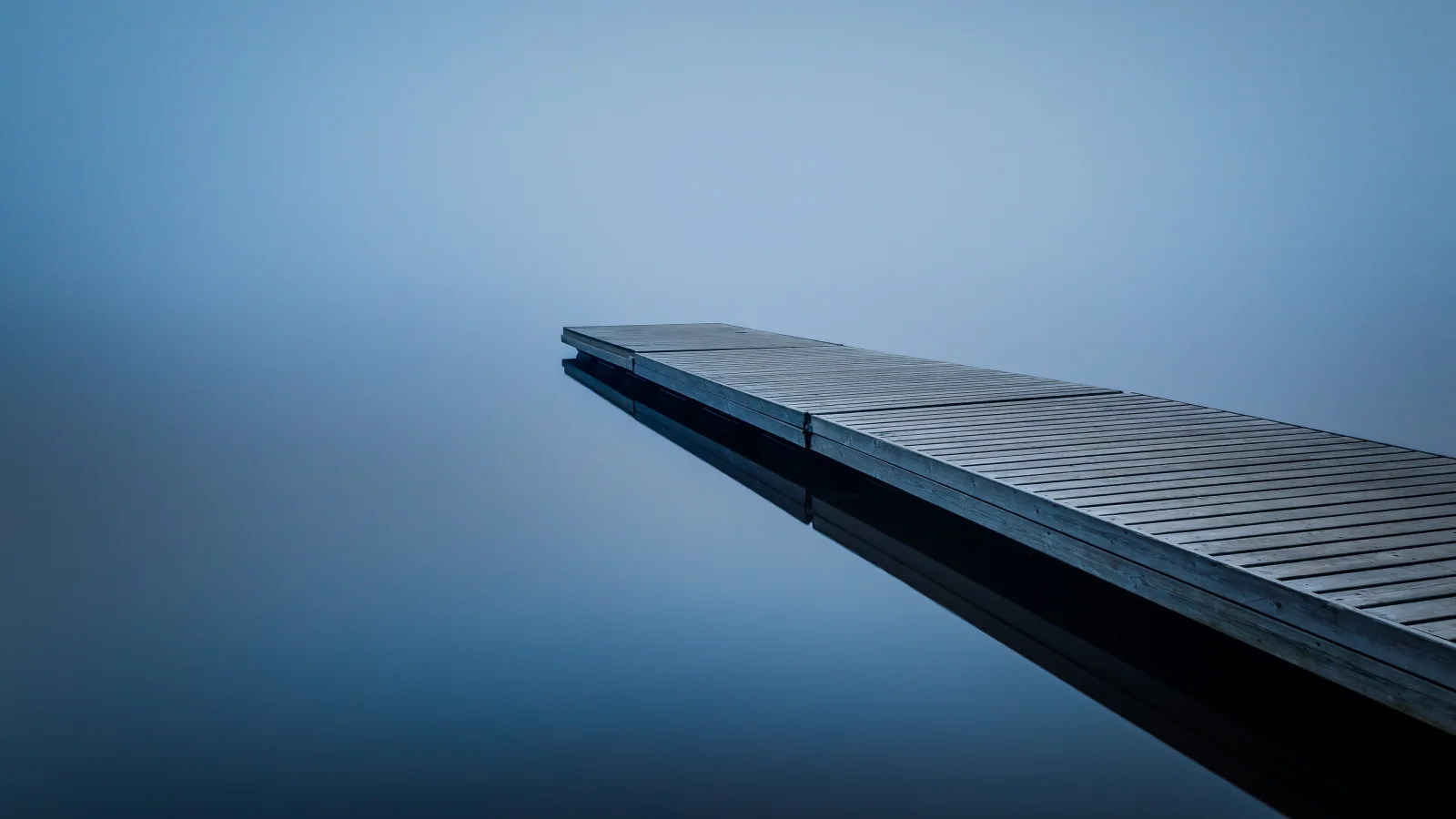 Hölzerner Brücke am See im Nebel