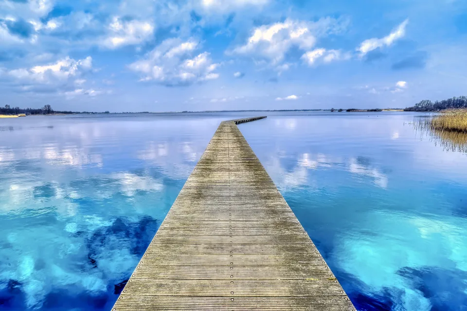 Hölzerner Brücke bei hellblauer Wasser See im Sommer