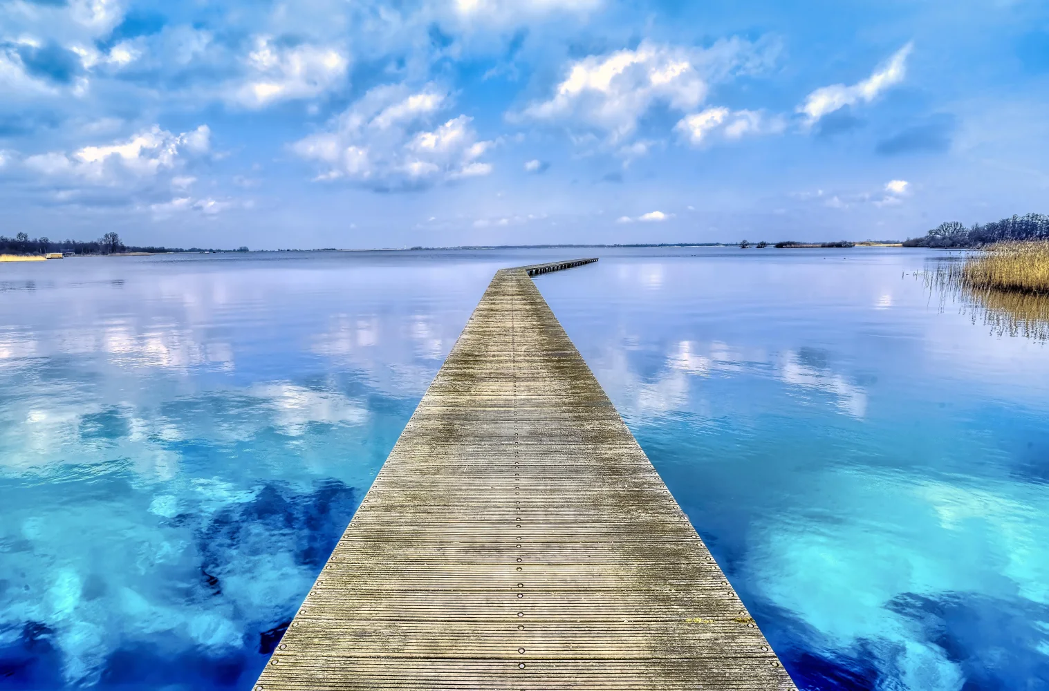 Hölzerner Brücke bei hellblauer Wasser See im Sommer